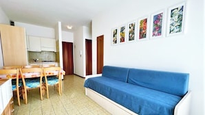 A compact living space with a kitchenette, a dining area with a table and chairs, and a blue sofa.