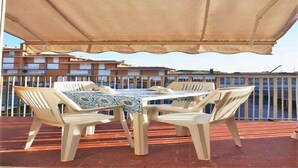 Un patio con mesa y sillas bajo un toldo, con vista a un cuerpo de agua.