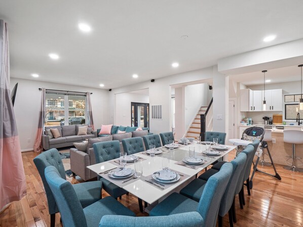 A modern dining area with a long table set for six, surrounded by blue upholstered chairs. - Colorful Large City Gatherings (Arlington)