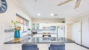 Cocina moderna con armarios blancos, encimera de granito y una isla central con taburetes de bar.