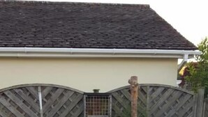 A hot tub with four people, a wooden fence, and a house in the background.