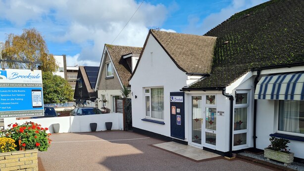 A guest house with a signboard advertising amenities like a spa, en suite rooms, and parking.
