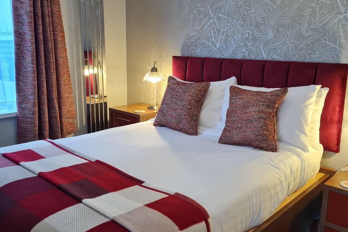 Ein Hotelzimmer mit einem großen Bett, einem roten Kopfteil und einer Wand mit Muster.