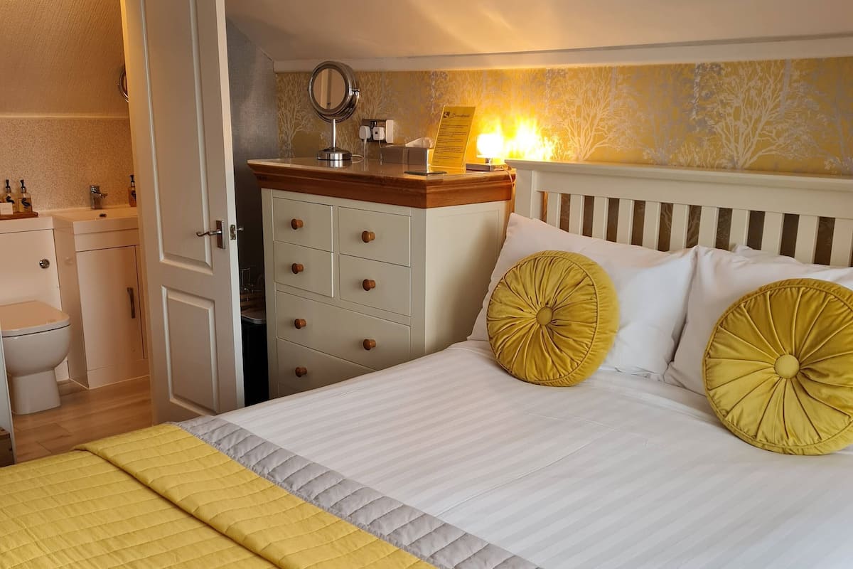 Ein Hotelzimmer mit Bett, Nachttisch mit Spiegel, Schrank und Toilette.