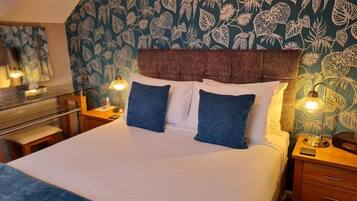 A neatly made bed with a headboard, two bedside tables with lamps, and a wall with a leafy pattern.