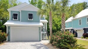 A two-story house with a garage, surrounded by palm trees and a well-maintained garden. - The Starfish: Near Huntington Beach State Park (Pawleys Island)