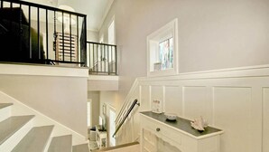 A staircase with a handrail, a white console table with decorative items, and a window with a view. - The Starfish: Near Huntington Beach State Park (Pawleys Island)