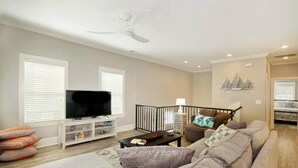 A living room with a sofa, television, and a ceiling fan. - The Starfish: Near Huntington Beach State Park (Pawleys Island)