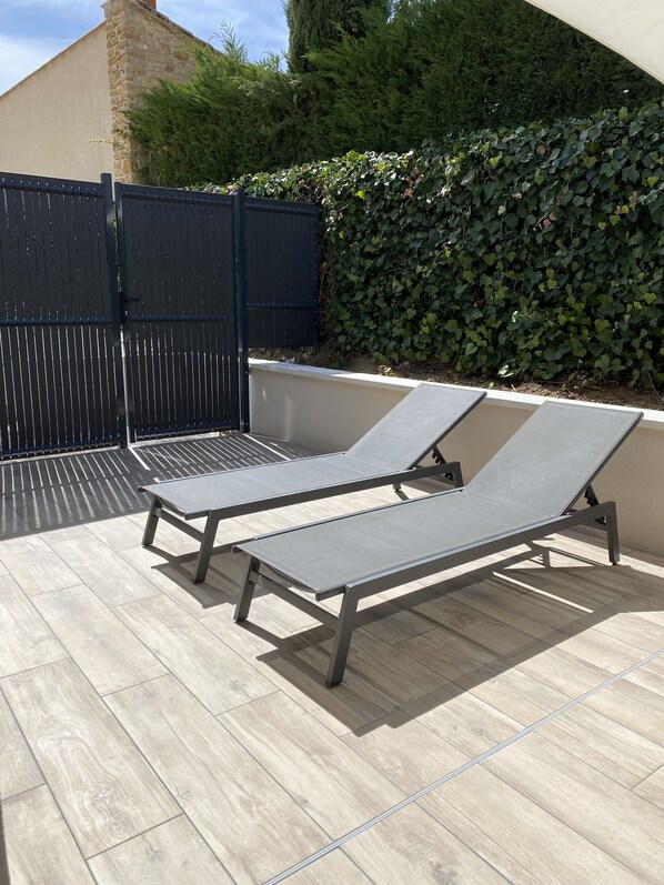 Terraza en la azotea con dos sillones de descanso y una barandilla de metal negro.
