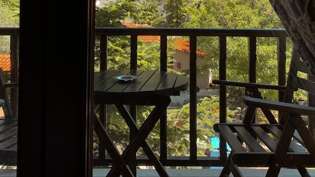 A balcony with a view of a mountainous landscape, a wooden table, and a bench. - Guesthouse Elena (Kalabaka)