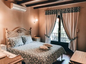 A bedroom with a bed, bedside table, and a window with curtains. - Guesthouse Elena (Kalabaka)