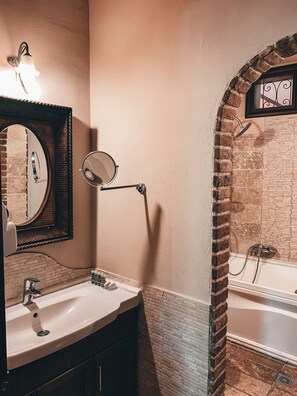 A bathroom with a white sink, a mirror, a towel rack, and a bathtub. - Guesthouse Elena (Kalabaka)