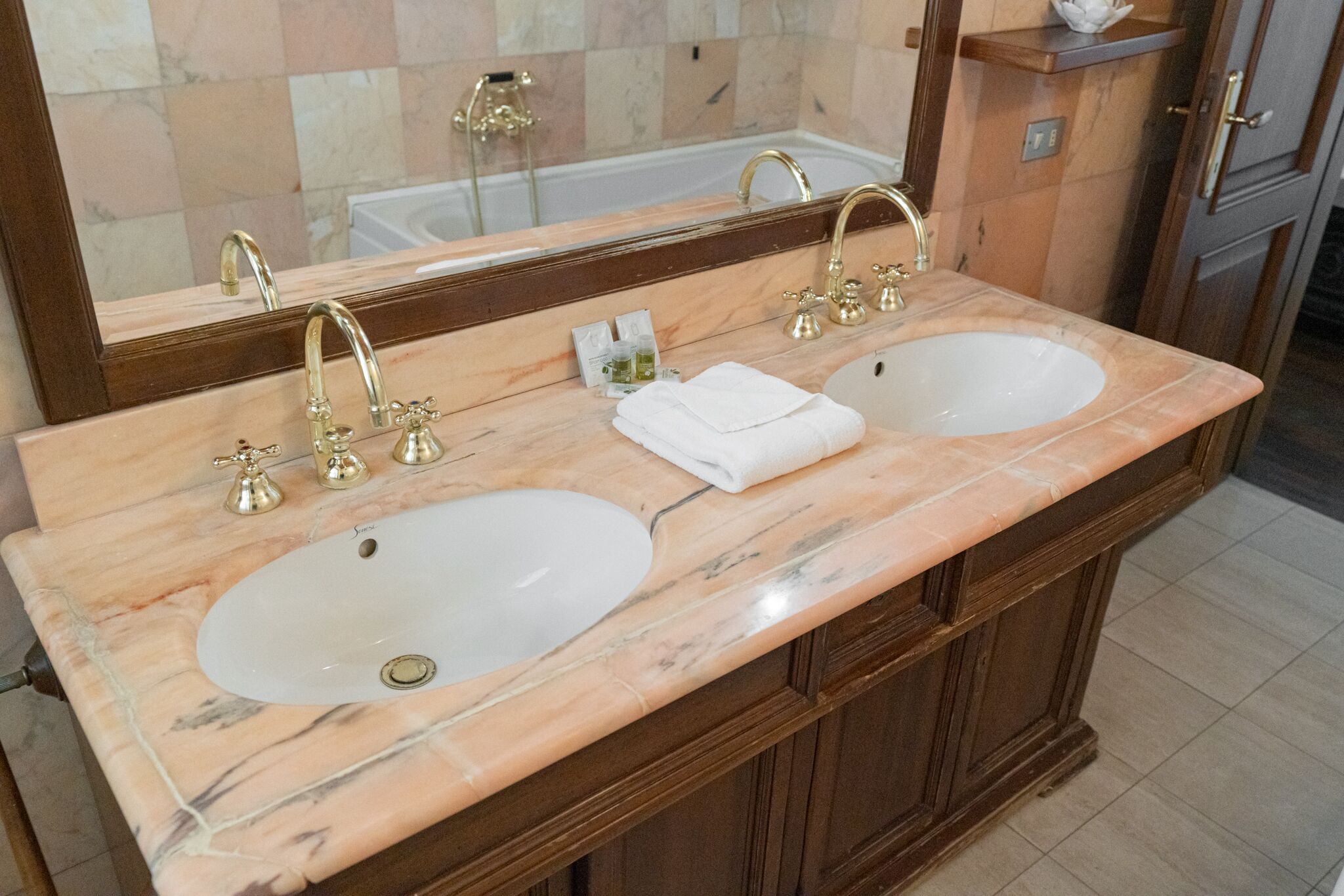 A bathroom with two sinks, a large mirror, and a bathtub.