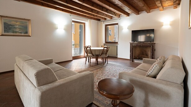 A living room with two sofas, a wooden coffee table, a fireplace, and a TV. - Residenza Cappello (Verona)