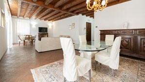 A dining area with a glass table and chairs, a wooden ceiling, and a chandelier. - Residenza Cappello (Verona)