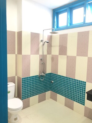 A bathroom with a toilet, a shower with a blue-tiled wall, and a window above the shower. - An's family homestay (Da Nang)