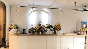 A reception area with a counter displaying various flowers and a sign that reads "Be Dum." - An's family homestay (Da Nang)