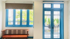 A room with a wooden bench, a window with blue frames, and a door with blue trim. - An's family homestay (Da Nang)