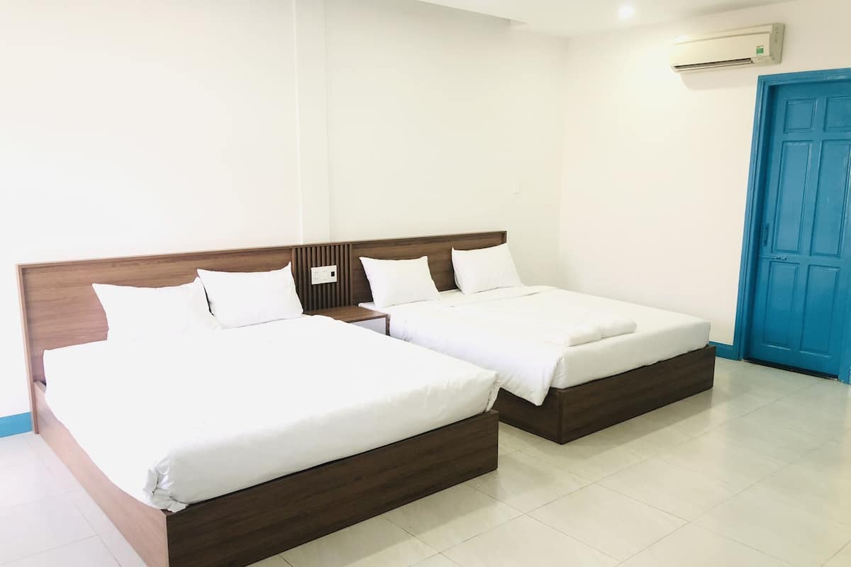A hotel room with two beds, a blue door, and an air conditioning unit on the wall.