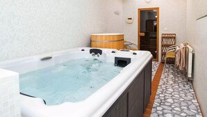 A spa room with a hot tub, wooden barrel, and a towel rack. - Hotel Dominika  (Bratislava)