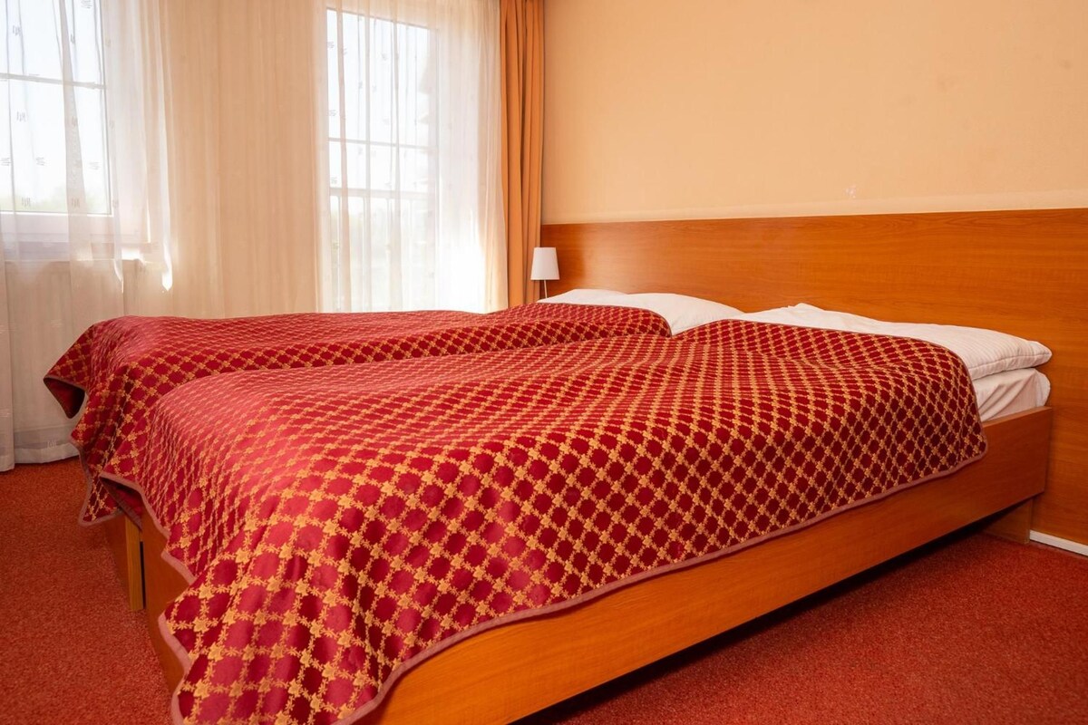 Una cama doble con cabecera de madera y colcha estampada roja.