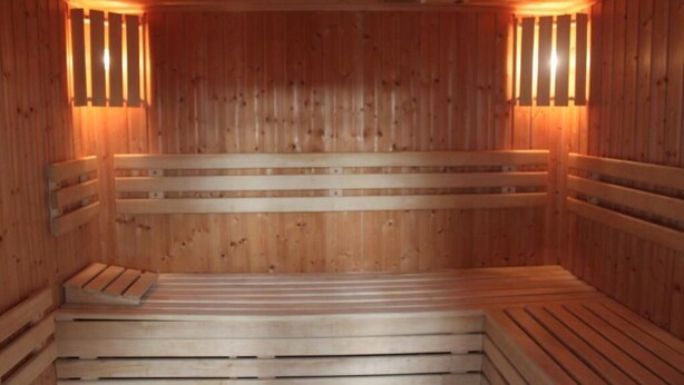 A wooden sauna with benches and wall-mounted lights. - Hotel Dominika  (Bratislava)