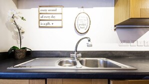 Une cuisine dotée d’un évier à deux bacs, de meubles en bois, d’une orchidée décorative et d’œuvres d’art murales inspirantes.