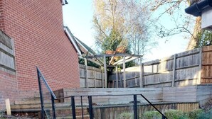 Une maison en briques avec une terrasse en bois et un escalier en métal.