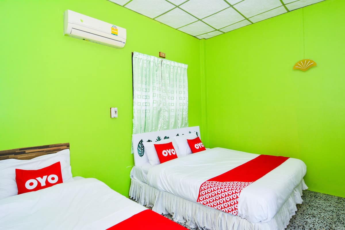 A room with two beds, each with a white and red bedspread, and a green wall.