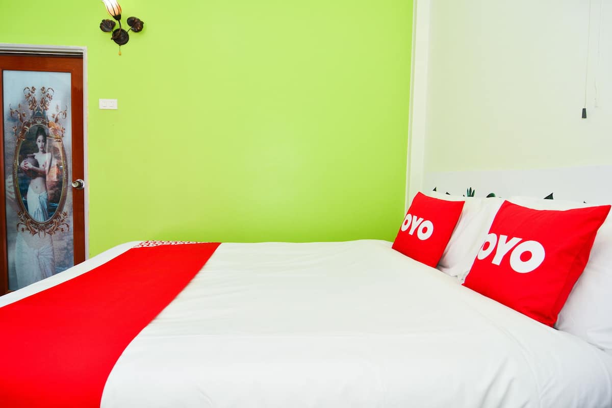 A bed with a red and white bedspread, two red pillows with the word "POYO" on them, and a green wall.
