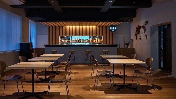 A modern restaurant with wooden paneling, a bar area, and multiple tables and chairs. - En Hostel Bar & Community Lounge (Kochi)