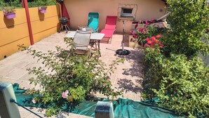 Une terrasse avec des meubles d’extérieur, un barbecue et un petit abri de jardin doté d’une porte.