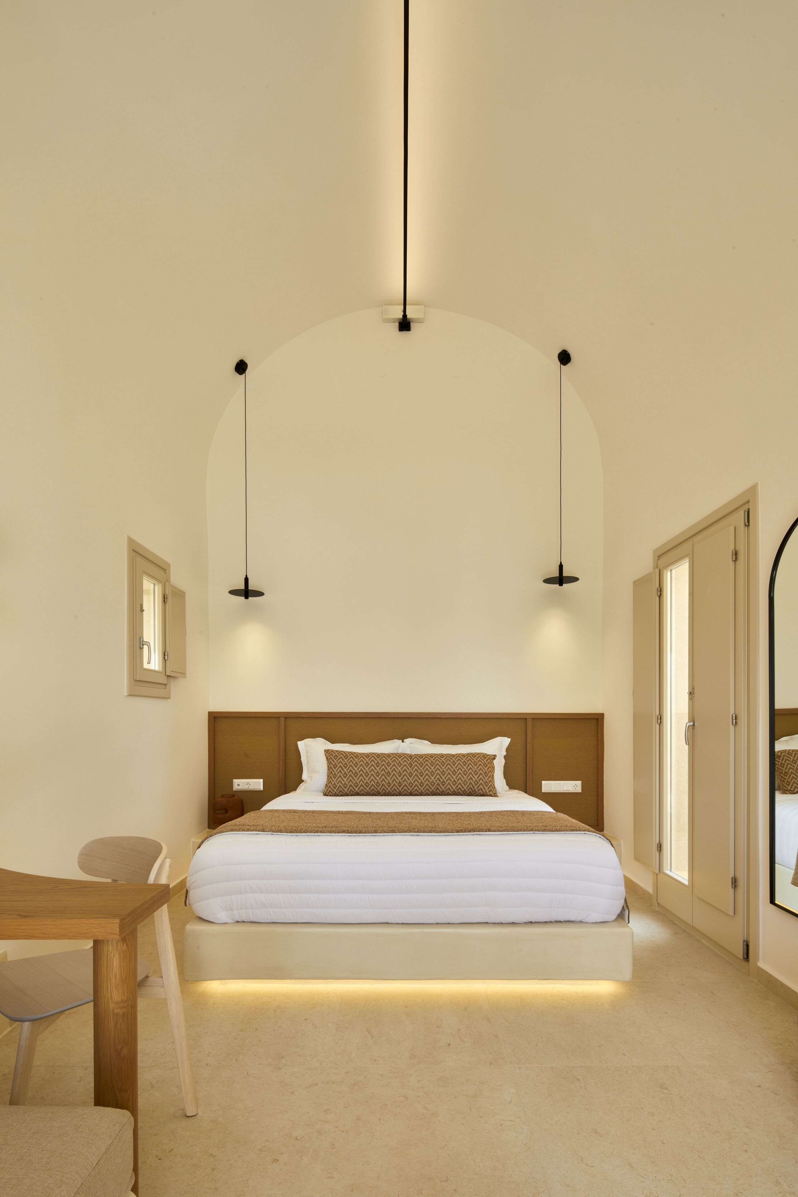 Una camera da letto con un letto, comodini, una sedia e uno specchio.