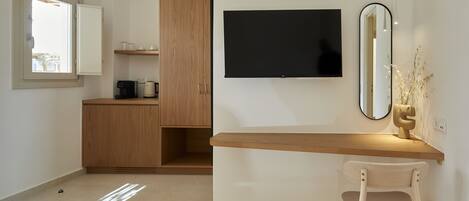 A modern room with a wooden desk, a television, a mirror, and a chair.