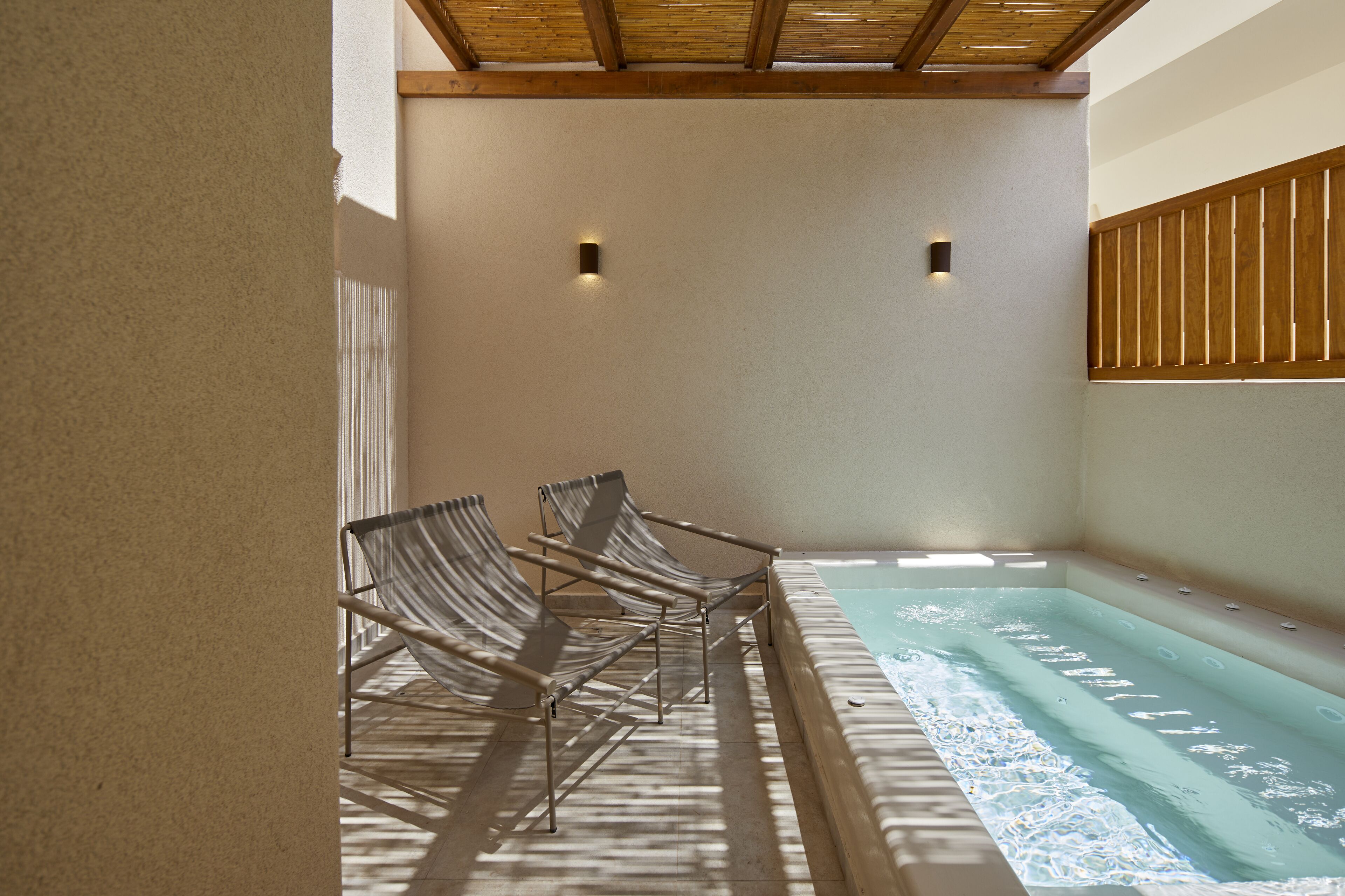 A spa area with a hot tub and two lounge chairs.