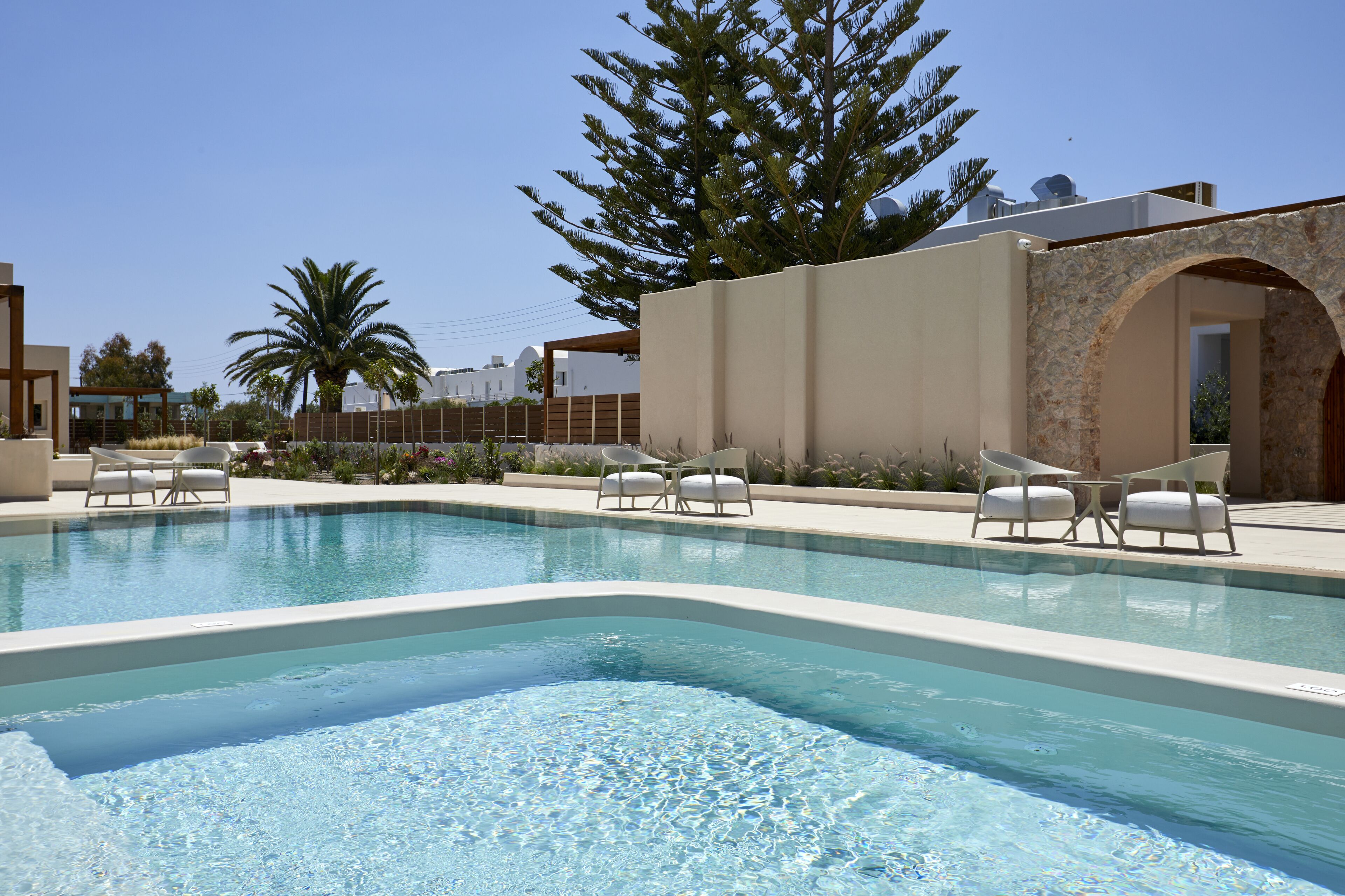 A swimming pool with lounge chairs and a stone wall.