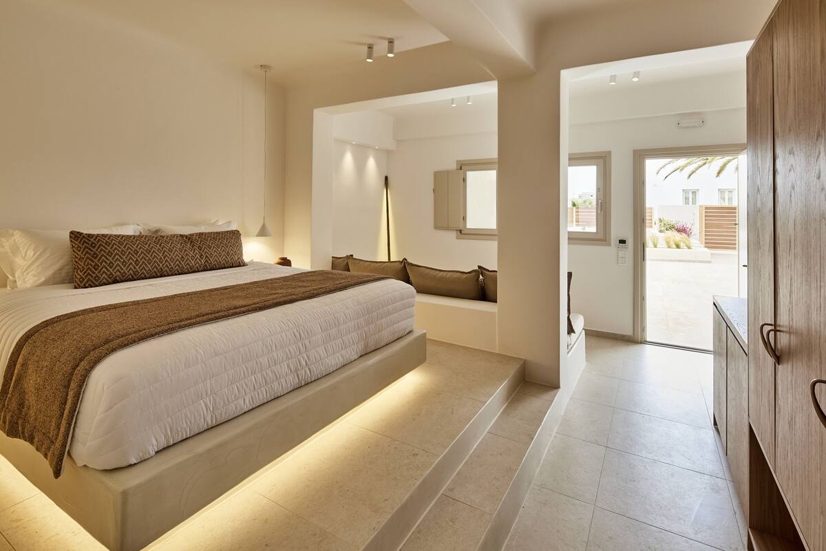 A modern bedroom with a large bed, a bedside table, and a wardrobe.