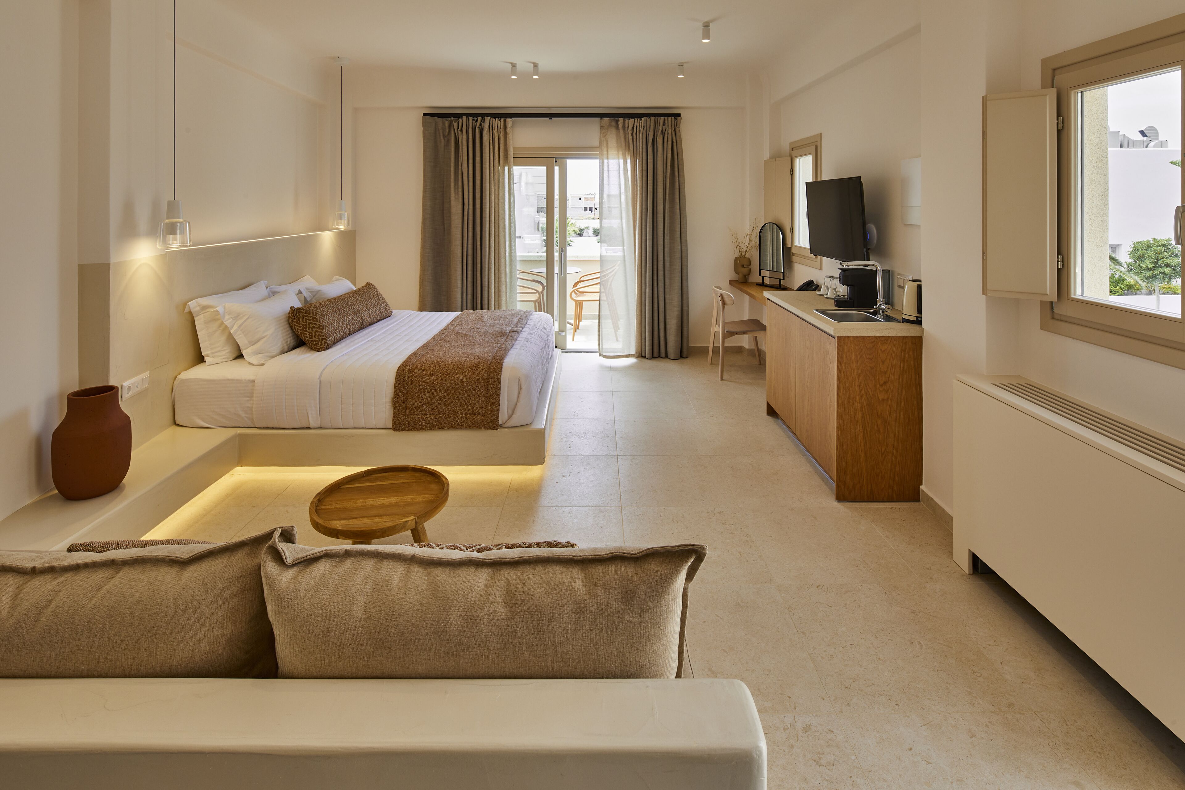 A modern hotel room with a bed, a desk, a television, and a view of the outdoors.