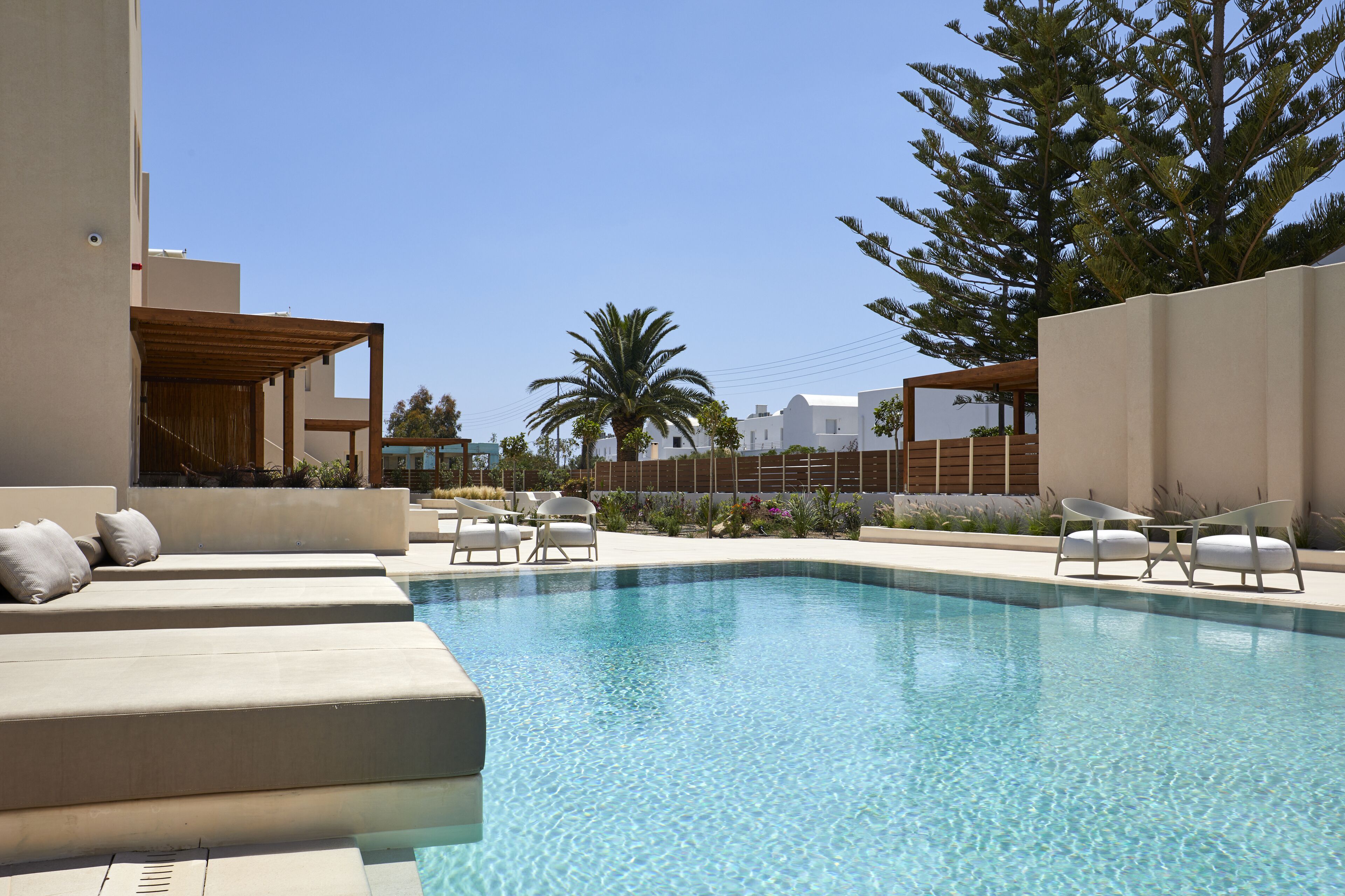 Una piscina con sillones de descanso y una pérgola.