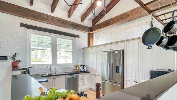 Una cucina con frigorifero in acciaio inox, soffitto in legno e un'ampia finestra.