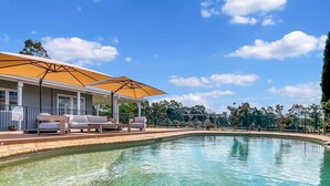 Piscina trasparente con terrazza in legno e zona relax all'aperto.