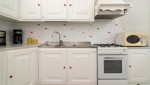 Una cocina con gabinetes blancos, cocina a gas, microondas y un fregadero.