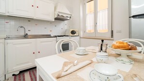 Una cocina con gabinetes blancos, estufa, fregadero y refrigerador.