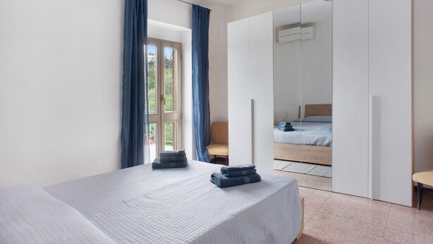 A bedroom with a bed, a chair, a wardrobe, and a window with curtains. - Holiday Home 'Da Chicca' with Countryside View, Wi-Fi & Air Conditioning (Bolano)