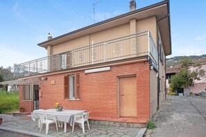 A two-story house with a balcony, a patio with a table and chairs, and a brick facade. - Holiday Home 'Da Chicca' with Countryside View, Wi-Fi and Air Conditioning (Bolano)