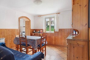 A wooden interior with a dining table, chairs, a sofa, a window with curtains, and a kitchenette. - Holiday Home 'Da Chicca' with Countryside View, Wi-Fi and Air Conditioning (Bolano)