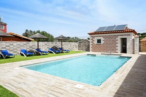 A rectangular swimming pool with blue lounge chairs and a small brick building with solar panels. - House 'Casa Torre de Meca 2' with Shared Pool and Mountain Views (Los Caños de Meca)