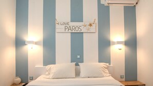A bedroom with a bed, two bedside tables, a wall-mounted sign, and a wall-mounted air conditioner. - Studio Apartment "Livadia Seaside 1" near Beach with 2 Shared Terraces & Wi-Fi (Paros)