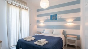 A bedroom with a bed, two bedside tables, a wall-mounted light, and a window with curtains. - Studio Apartment 'Livadia Seaside Studios 7' with Shared Terrace, Wi-Fi, and Air Conditioning (Paros)