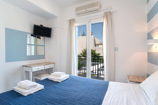 A hotel room with a bed, a desk, a TV, a balcony with a view, and a sliding door.